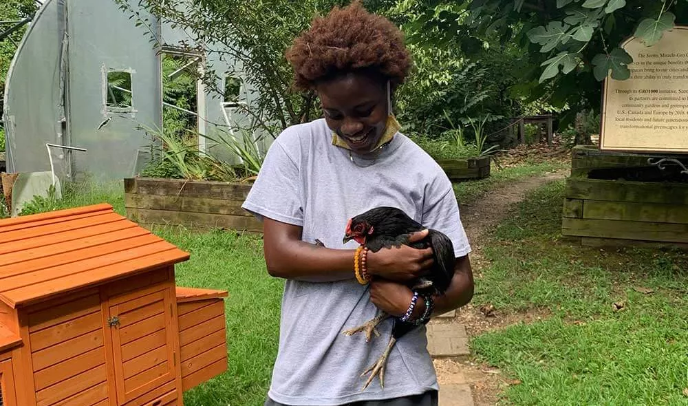 Covenant Home resident Ann holding a chicken in a yard