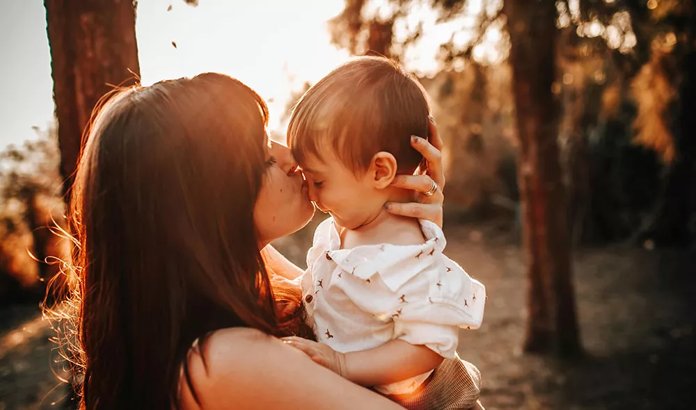 young mother holding and kissing child | Covenant Home - Photo by Helena Lopes