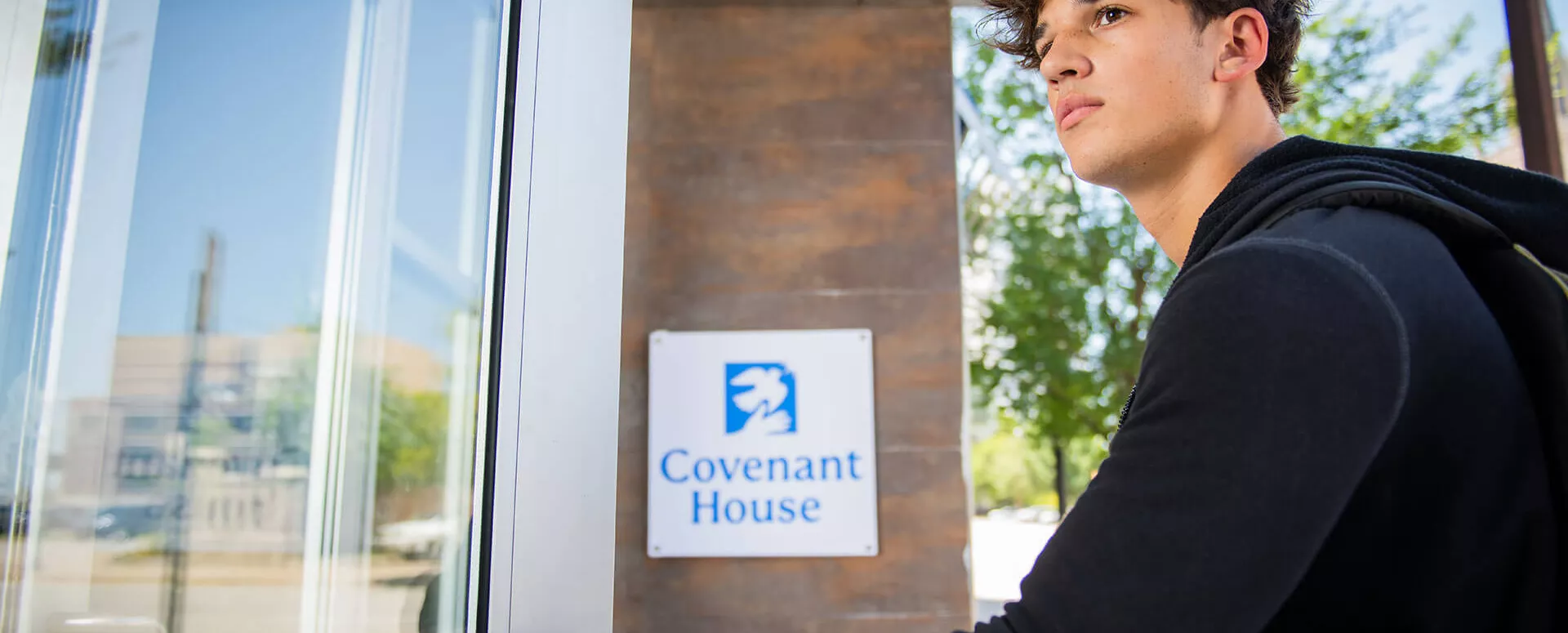 Young man opening a door. Covenant Home is open 24/7.