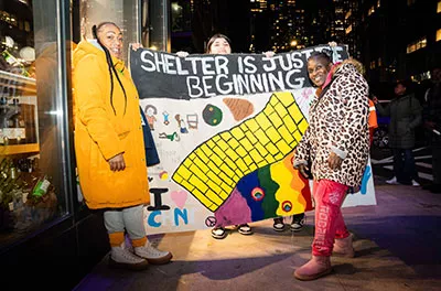 Covenant Home Sleep Out volunteers with big art poster saying "Shelter Is Just The Beginning" | Raising funds and awareness for homeless youth