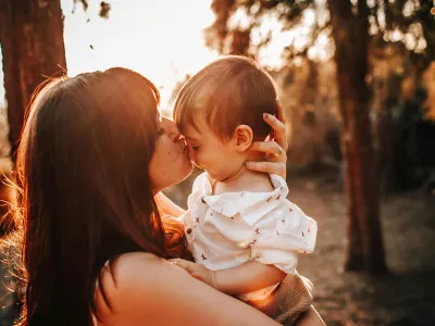 young mother holding and kissing child | Covenant Home - Photo by Helena Lopes