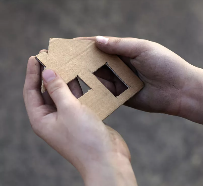 Hands carrying cardboard cut house | Covenant Home - Be an Advocate