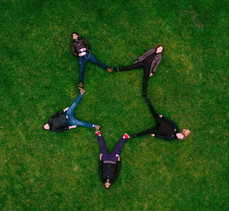 former homeless teens forming a star while lying down on grass | Covenant Home - DIY Fundraise